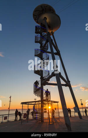 Bournemouth, Dorset, UK. 27th Dec, 2018. Beautiful sunset over Bournemouth beach at the end of a lovely sunny day, as visitors head to the pier and beach to watch the sun go down. The spiral structure of the zipline zipwire launch tower on Bournemouth Pier silhouetted with sunburst. Zipliners climb to the top of the launch tower structure at the end of the pier. Credit: Carolyn Jenkins/Alamy Live News Stock Photo