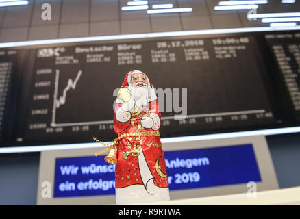 Frankfurt, Germany. 28th Dec, 2018. A chocolate Santa Claus stands in front of the display board with the DAX curve in the trading room of the Frankfurt Stock Exchange. After the losses on the previous day, share prices rose again on the last trading day of the year. Overall, the German share index (DAX) has lost almost 20 percent since the beginning of the year. Photo: Arne Dedert/dpa Credit: dpa picture alliance/Alamy Live News Stock Photo