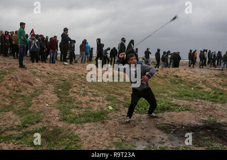 (181229) -- BEIJING, Dec. 29, 2018 (Xinhua) -- A Palestinian protester hurls stones at Israeli troops during clashes at the Gaza-Israel border, east of Gaza City, on Dec. 28, 2018. At least six Palestinian protesters were injured on Friday afternoon by Israeli soldiers' gunfire during clashes in eastern Gaza Strip, close to the border with Israel, medics said. (Xinhua) XINHUA PHOTOS OF THE DAY Stock Photo