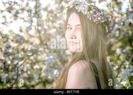 Beautiful girl in spring garden with blooming apple trees. Young natural woman portrait, outdoors. Stock Photo