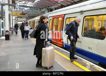 People waiting on the platform with luggage boarding a Hammersmith and City tube train in an underground station in London England UK  KATHY DEWITT Stock Photo