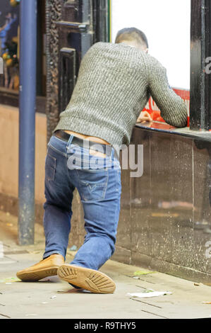 Pictured: A man attempts to stand on his feet. Friday 14 December 2018 Re: Revellers in Wind Street, Swansea, Wales, UK. Stock Photo