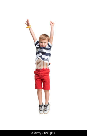 Adorable blond boy jumping and raises his hands up. Isolated on white background. Shooting in the studio Stock Photo