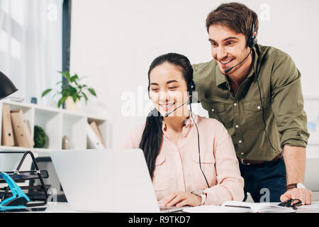 call center operators smiling and looking at laptop screen in office Stock Photo