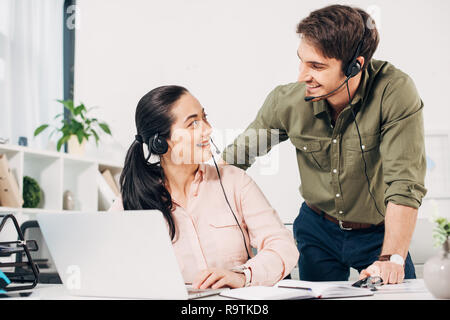 call center operators smiling and looking to each other in office Stock Photo