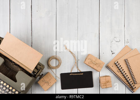 Writer's workplace - vintage typewriter, notepads, present boxes and mini blackboard on the white wooden background Stock Photo