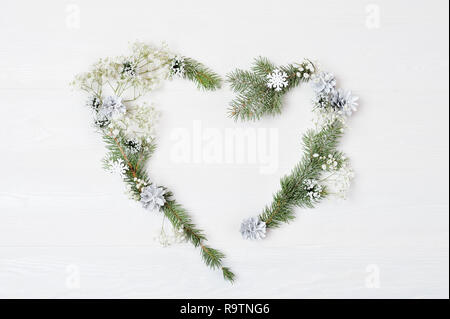 Mockup of Christmas Wreath in form of heart Decorated with white snowflakes and cones. On white wooden background, Flat lay with place for your text. Top view Stock Photo