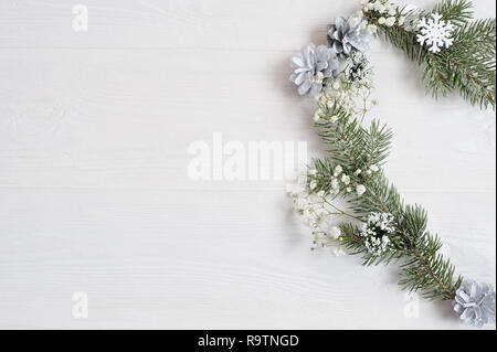 Mockup of Christmas Wreath in form of heart Decorated with white snowflakes and cones. On white wooden background Stock Photo