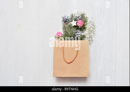 Christmas mockup. Kraft package with xmas decor fir branches, pink roses, cones with place for your text. Shopping concept Stock Photo