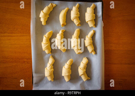 Raw croissant roll dough on parchment paper and pan ready for the oven Stock Photo