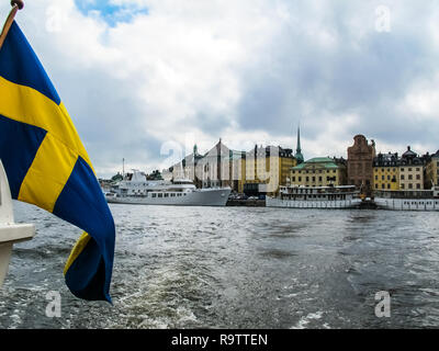 Panoramic view from the excursion boat with the flag of Sweden on tourist boats and waterfront houses in Gamla Stan. Stockholm Sweden Stock Photo
