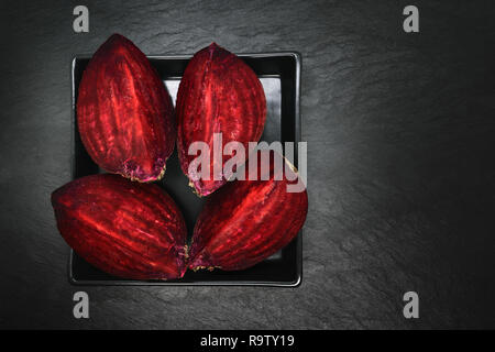 Abstract composition of four pieces chopped beetroot placed on black plate and black stone background Stock Photo