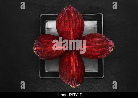 Abstract composition of four pieces chopped beetroot placed on black plate and black stone background Stock Photo