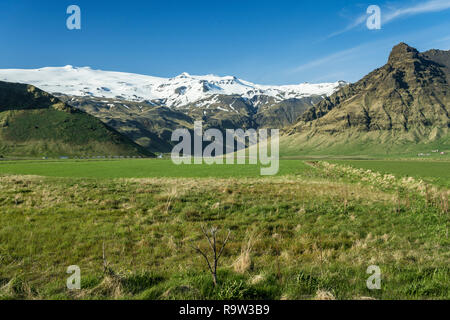 A green meadow and snow capped mountain range in southern Iceland, Europe. Stock Photo