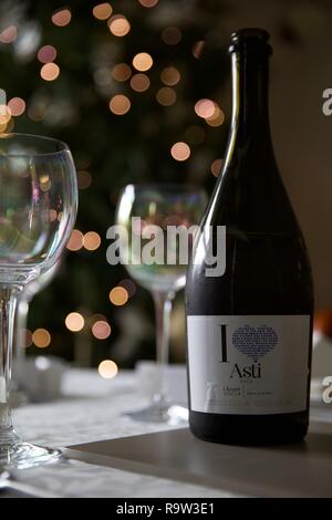 Wine glasses and a bottle of Asti with Christmas lights in the background Stock Photo