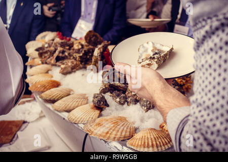 Plates with oysters in the hands of visitors corporative Stock Photo