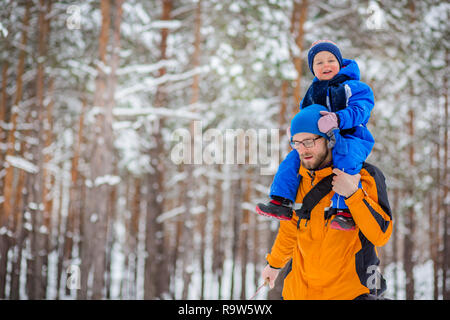 Father walks with his young children in the woods in winter. Winter activities in the snow, sleds and snowballs Stock Photo