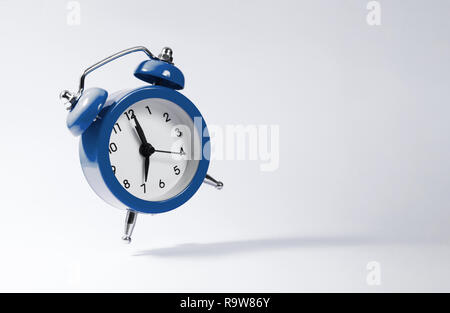 The dark blue alarm clock bounces against the background. Stock Photo