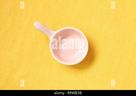 Pink ceramic bowl on yellow fabric background Stock Photo