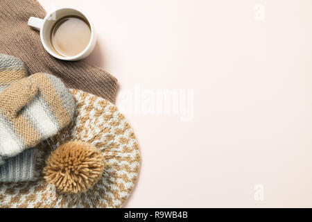 Mug coffee and warm knitted hat, gloves on pink background. Winter season concept Stock Photo