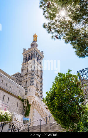 Low angle view of the bell tower of Notre-Dame de la Garde basilica in Marseille, France, with the golden statue of the Madonna and Child at the top. Stock Photo