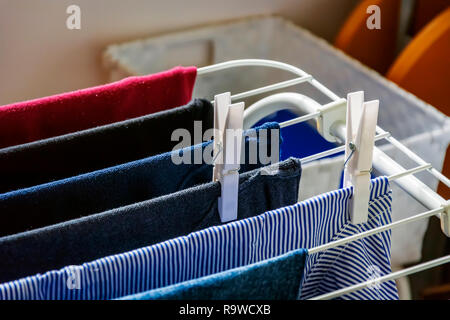 white clothespins hanging a clothes hanging on a drying rack. Drying laundry Stock Photo