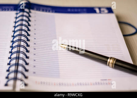 a black pen on an open spiral notebook. Business and scheduling concept Stock Photo