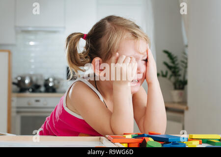 Charming preschooler playing with wooden constructor. Little girl playing with connecting pieces Stock Photo
