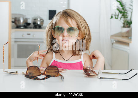 Portrait of cute little girl trying to wear glasses Stock Photo