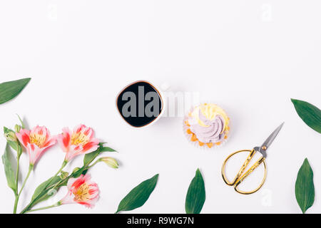 View from above cup of coffee and dessert on white table near decorative flat layout of lily flowers. Stock Photo