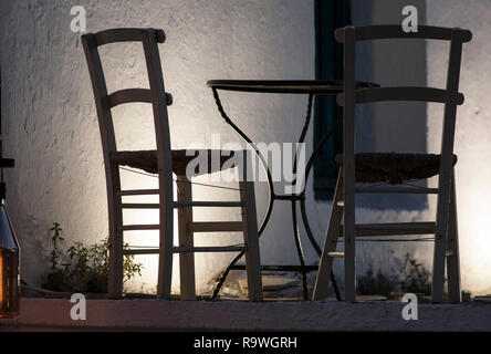 two lonely chairs and table on twilight, Greece; Amouliani island Stock Photo