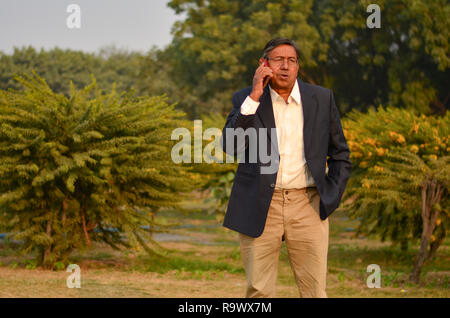 Senior Indian man speaking on his phone at a park in Delhi, India Stock Photo