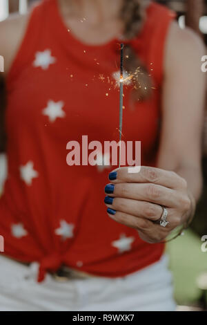 A girl in a star shirt holding a sparkler on the 4th of July in the United States of America (USA). Stock Photo