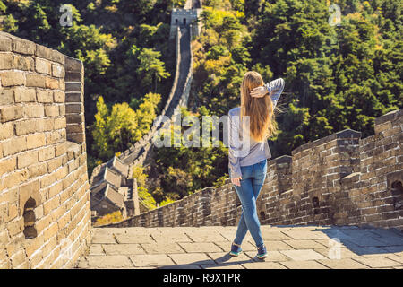 Happy cheerful joyful tourist woman at Great Wall of China having fun on travel smiling laughing and dancing during vacation trip in Asia. Girl visiting and sightseeing Chinese destination Stock Photo