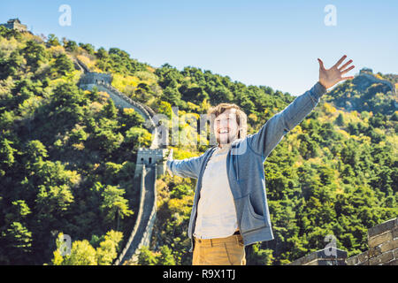 Happy cheerful joyful tourist man at Great Wall of China having fun on travel smiling laughing and dancing during vacation trip in Asia. Man visiting and sightseeing Chinese destination Stock Photo