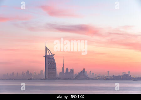 Stunning view of Dubai skyline from Jumeirah beach to Downtown lighted with warm pastel sunrise colors. Dubai, UAE. Stock Photo