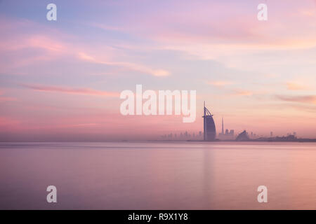 Stunning view of Dubai skyline from Jumeirah beach to Downtown lighted with warm pastel sunrise colors. Dubai, UAE. Stock Photo