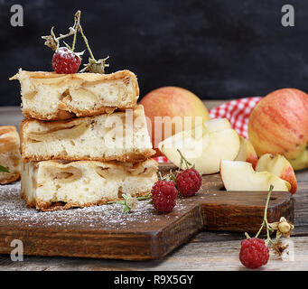 pieces of apple pie are stacked on a brown wooden board, sponge cake Stock Photo