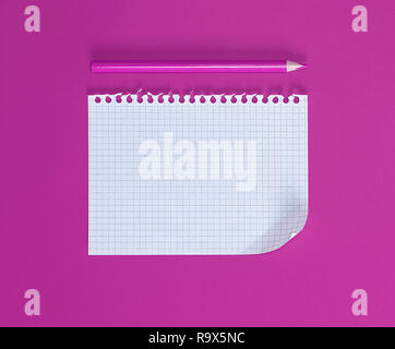 empty rectangular white sheet torn out of notepad and wooden pencil on a pink background Stock Photo
