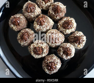 Chocolate homemade cookies decorated with cocoa cream and grated hazelnuts on the black plate, top view Stock Photo