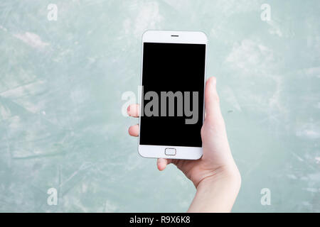 Touch screen white smartphone with black screen in boy hand on green grounge background Stock Photo