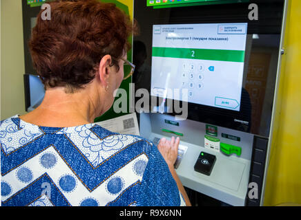Voronezh, Russia - July 14, 2018: Elderly woman enters meter readings in payment terminal Stock Photo