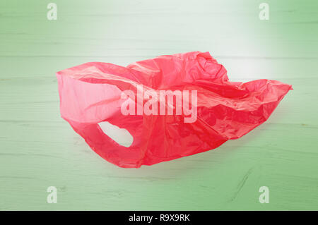 Floating empty red plastic garbage bag on green wooden background. Stock Photo