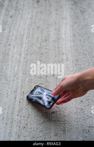 Hand holding phone with broken screen by hammer Stock Photo