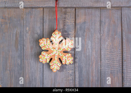 Gingerbread snowflakes cookies for Christmas hanging on wooden background. Stock Photo