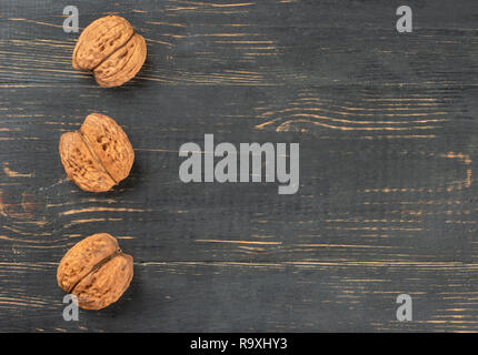 Three dry walnuts on an empty wooden background, top view Stock Photo