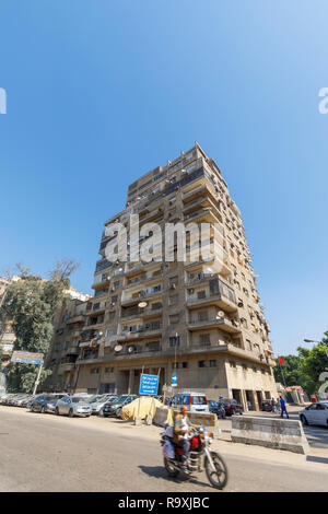 Street scene in Giza, Cairo, Egypt with typical large roadside residential apartment block with satellite dishes and external air-conditioning units Stock Photo