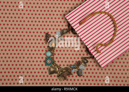 Celebratory concept - handmade striped shopping bag of craft paper, gift bags and women's jewelry on craft  paper background in red polka dots
