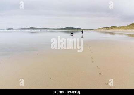 Woman walking her dog along Machir Bay, Traigh Mhachir beach, Rhinns of Islay, Inner Hebrides, Argyll & Bute, Scotland Stock Photo