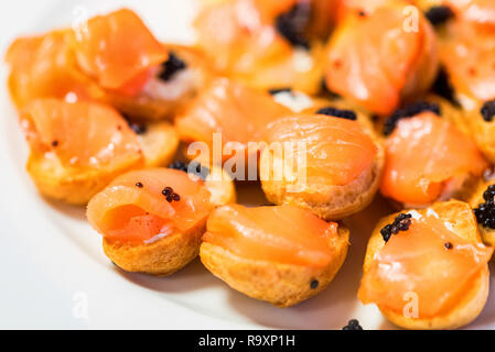 Close up fresh tasty profiterolies with salmon and black caviar Stock Photo